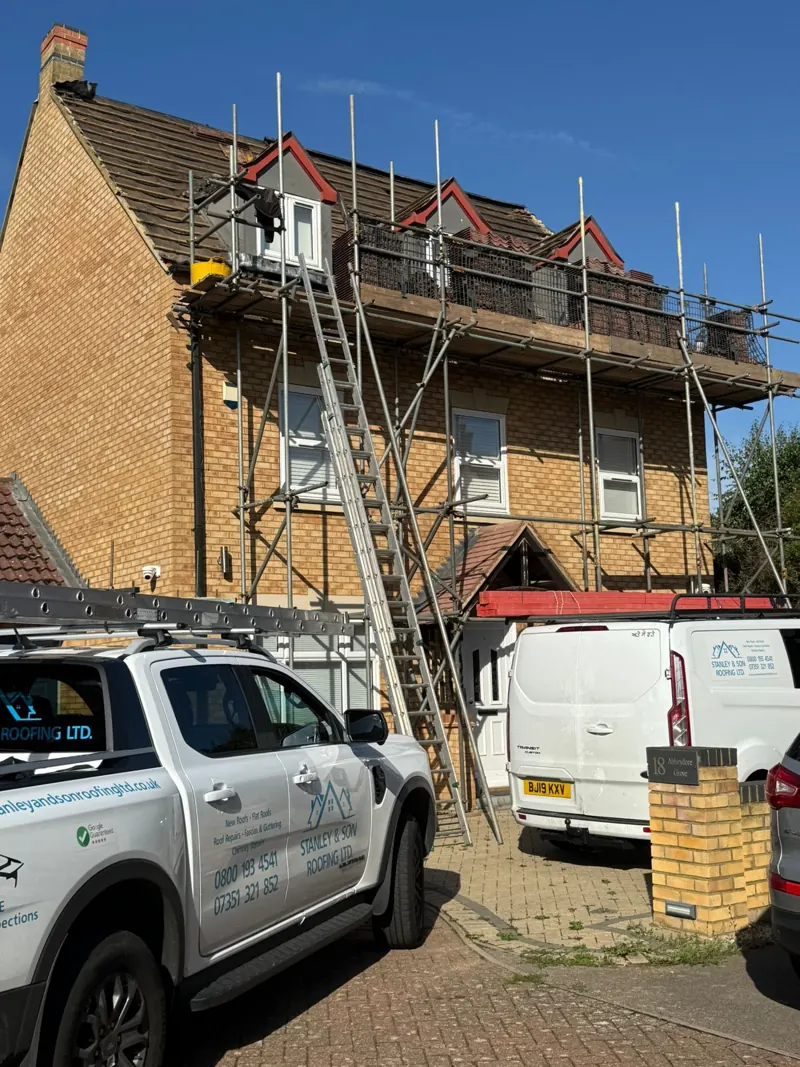 Scaffold erected to the front of the three-storey house with the Stanley & Son Roofing pick-up and van on site