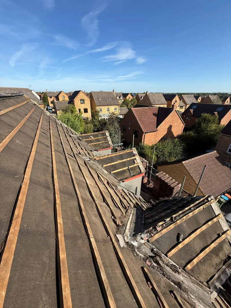 Roof stripped back to the old felt and battens, showing the worn underlay and dormer abutments before the rebuild